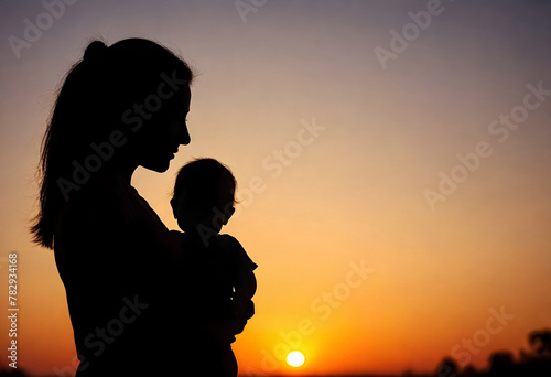 silhouette of a mother holding her baby at sunset
