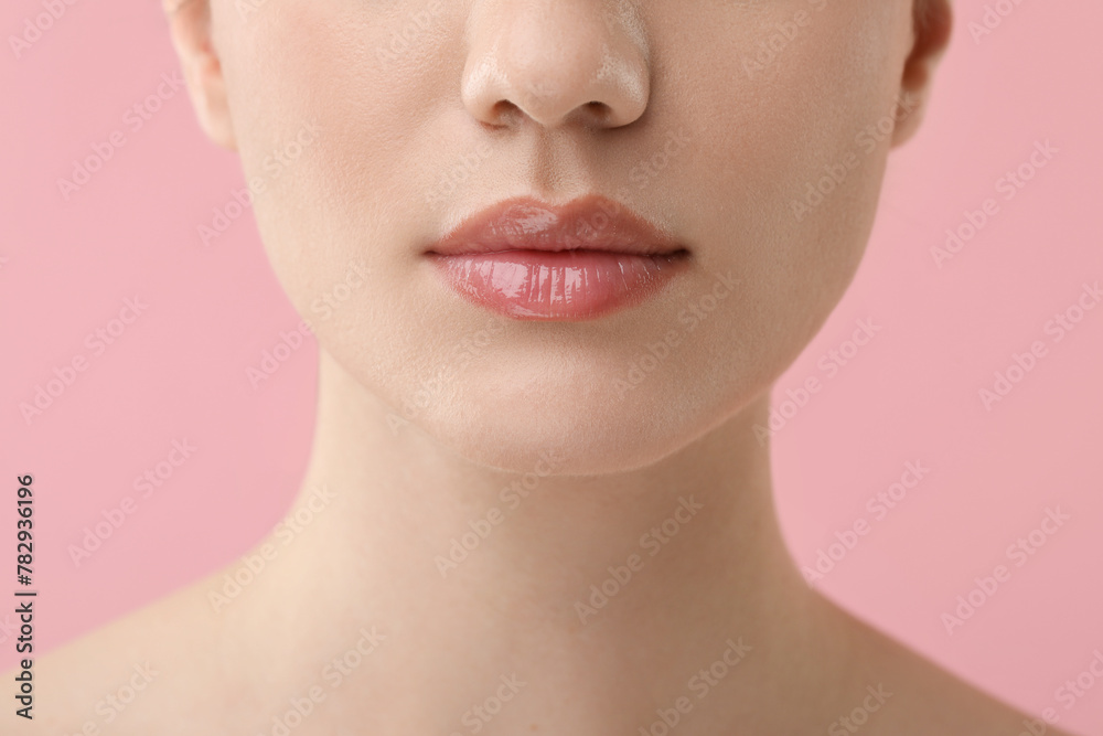 Woman wearing beautiful lip gloss on pink background, closeup Woman wearing beautiful lip gloss on pink background, closeup