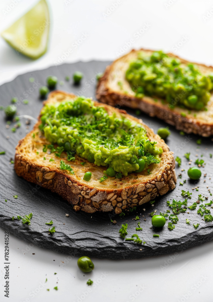 Gourmet toast, topped with smashed peas, on slate plate, isolated on white background. 