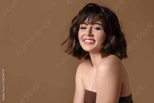 Portrait of beautiful young woman with wavy hairstyle on brown background. Space for text