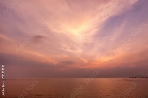 a bright sky over the ocean as the sun sets behind © Wirestock