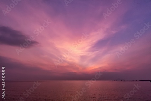 the sun sets behind a bright purple sky over water and a small jett in the © Wirestock