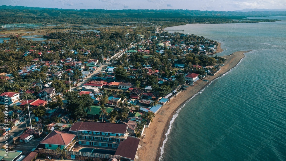 Aerial of a coastal residential area with similar buildings and the turquoise sea washing the shore