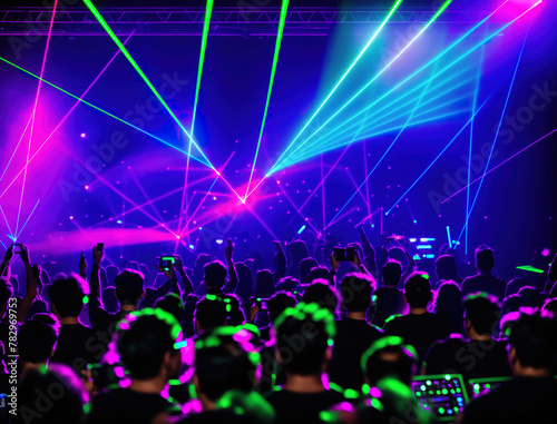 A large crowd of people at a concert or festival, with bright lights shining down on them.