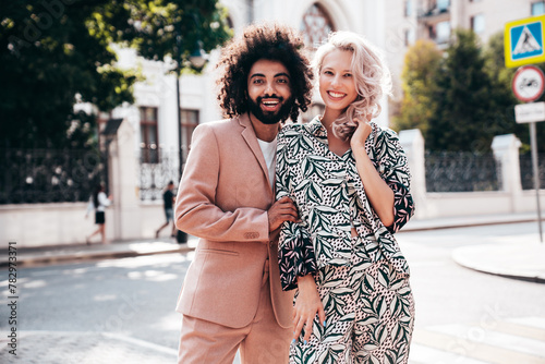 Beautiful fashion woman and her handsome elegant boyfriend in beige suit. Sexy blond model in summer suit clothes. Fashionable smiling couple posing in street Europe. Brutal man and female outdoors © halayalex