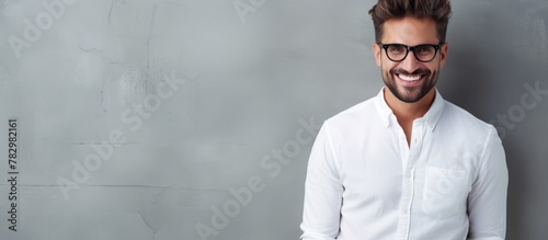 Man in eyeglasses smiling by gray wall photo