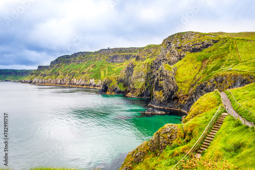 View from Carrick-a-Rede Rope Bridge, famous rope bridge near Ballintoy in County Antrim, Northern Ireland on Irish coastline. Tourist attraction, bridge to small island on cloudy day.