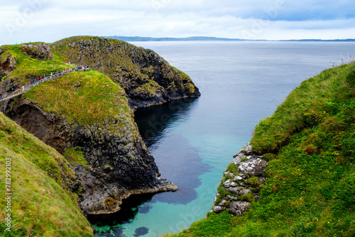 View from Carrick-a-Rede Rope Bridge, famous rope bridge near Ballintoy in County Antrim, Northern Ireland on Irish coastline. Tourist attraction, bridge to small island on cloudy day. photo