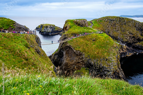 View from Carrick-a-Rede Rope Bridge, famous rope bridge near Ballintoy in County Antrim, Northern Ireland on Irish coastline. Tourist attraction, bridge to small island on cloudy day.