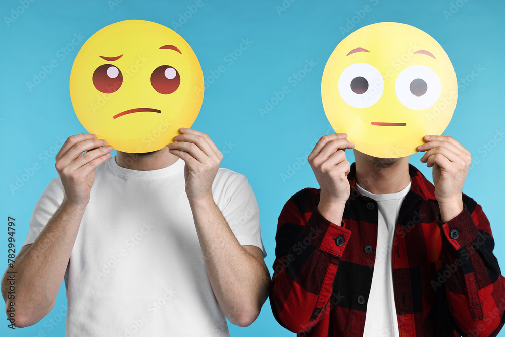 People covering faces with emoticons on light blue background People covering faces with emoticons on light blue background