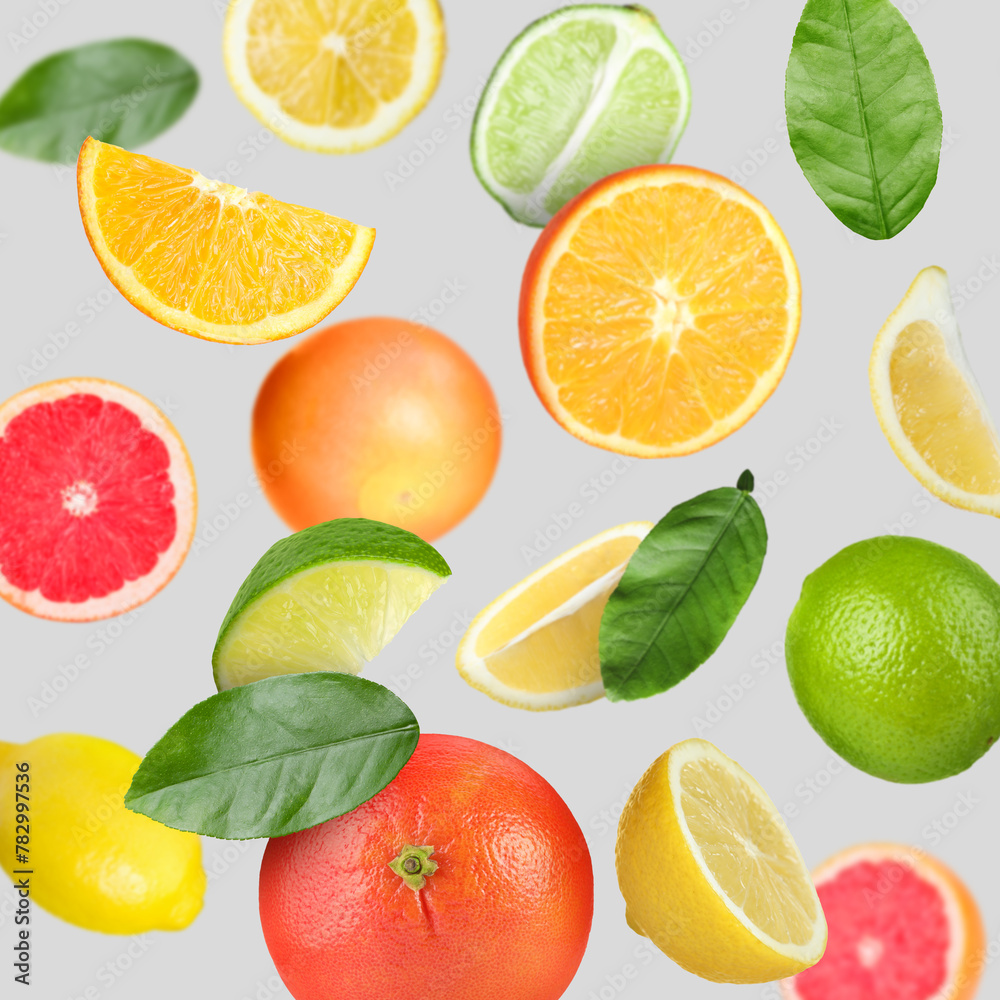 Many different fresh citrus fruits in air on light grey background