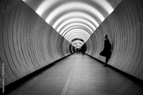 A woman standing against a wall in a tunnel