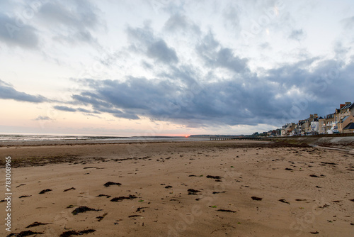 Sunrise view of coastal street of Grandcamp Maisy, a scenic French coastal town in Normandy, with fishing port, sandy beaches, and maritime traditions.