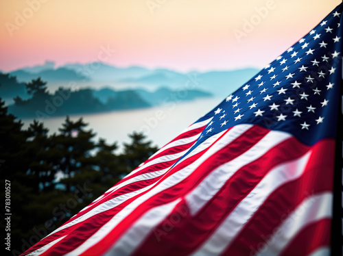 An American flag waving in the wind with mountains in the background.