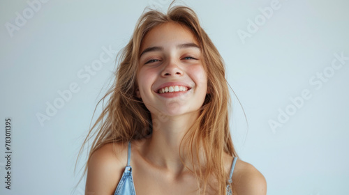 A happy teenage girl exuding joy and confidence while standing against a solid white background.