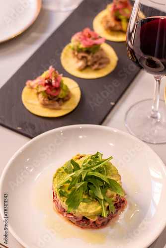 Mesa puesta con platos aesthetic frescos de tartar, mini tacos y vino tinto