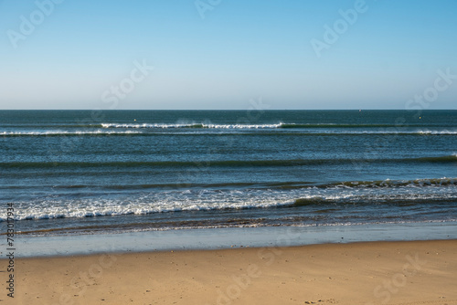 Detail of the waves of the Atlantic sea beating on the golden sand beach during the summer holidays in the province of Huelva, Spain.