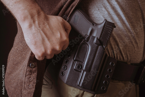 A gun in a holster, delicately hidden under his shirt.