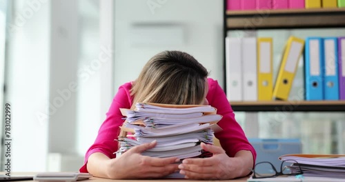 Tired office worker is overloaded with paperwork in office photo
