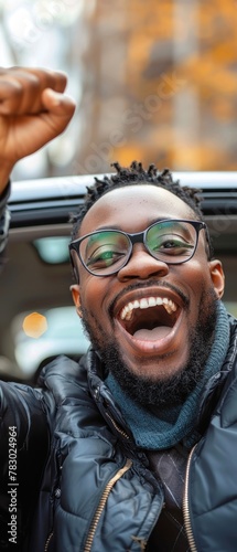 A man with glasses and a beard is smiling and holding his hands up in the air