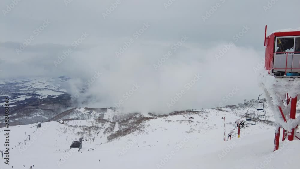 Niseko, Japan: Skiers who rides a red chairlift in the famous Niseko ski resort in Hokkaido on a foggy cold winter day in northern Japan Niseko, Japan: Skiers who rides a red chairlift in the famous Niseko ski resort in Hokkaido on a foggy cold winter day in northern Japan