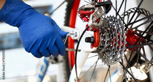Male repair man bicycle service in blue protective gloves adjusts bike to prepare for the season concept closeup