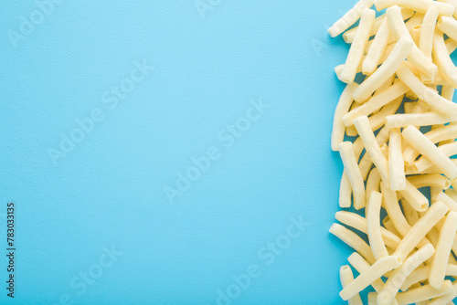 White potato chips sticks on light blue table background. Pastel color. Closeup. Empty place for text. Top down view.