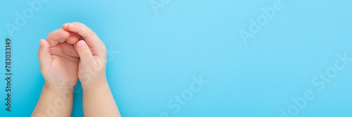 Baby boy opened palms on light blue table background. Pastel color. Closeup. Point of view shot. Empty place for text. Wide banner. Top down view.