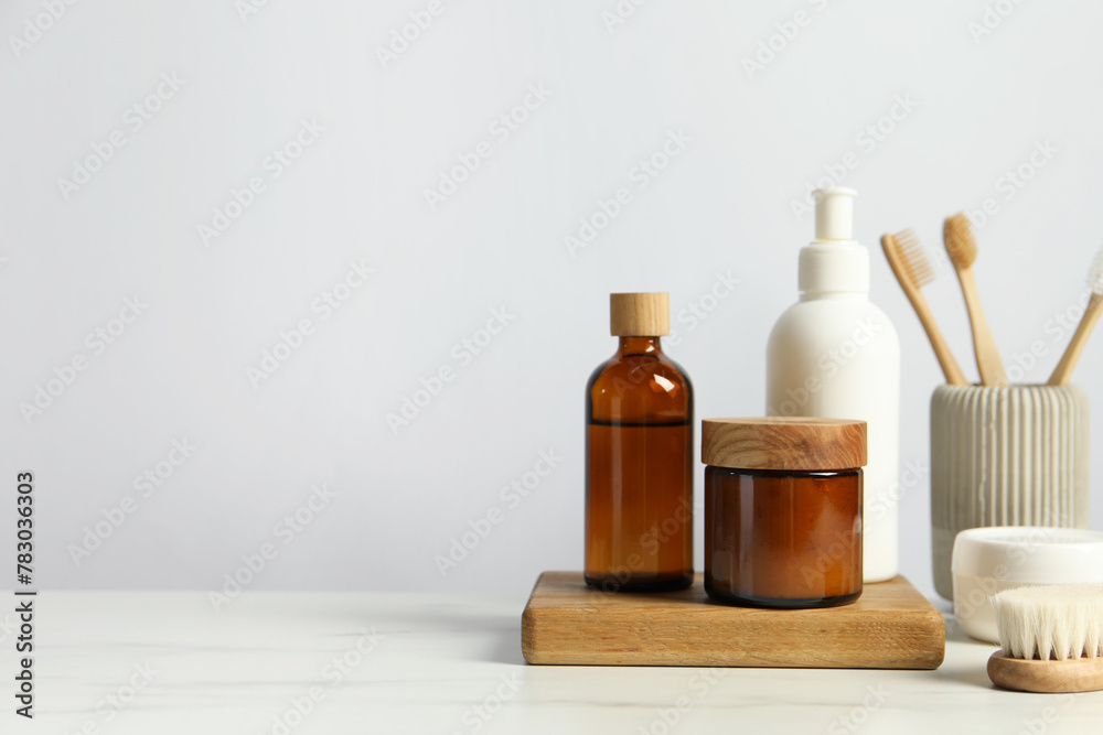 Different bath accessories and personal care products on light marble table against white wall, space for text Different bath accessories and personal care products on light marble table against white wall, space for text