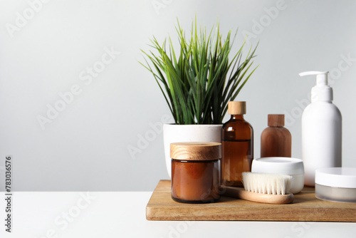 Different bath accessories and houseplant on white table against grey background. Space for text