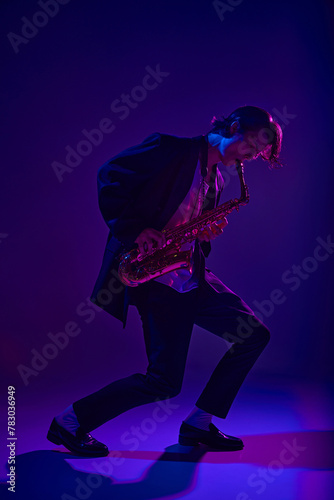 Talented jazz man, virtuoso playing saxophone in vibrant pink neon light against dark studio background. Concept of music and art, hobby, concerts and festivals, modern culture. Ad