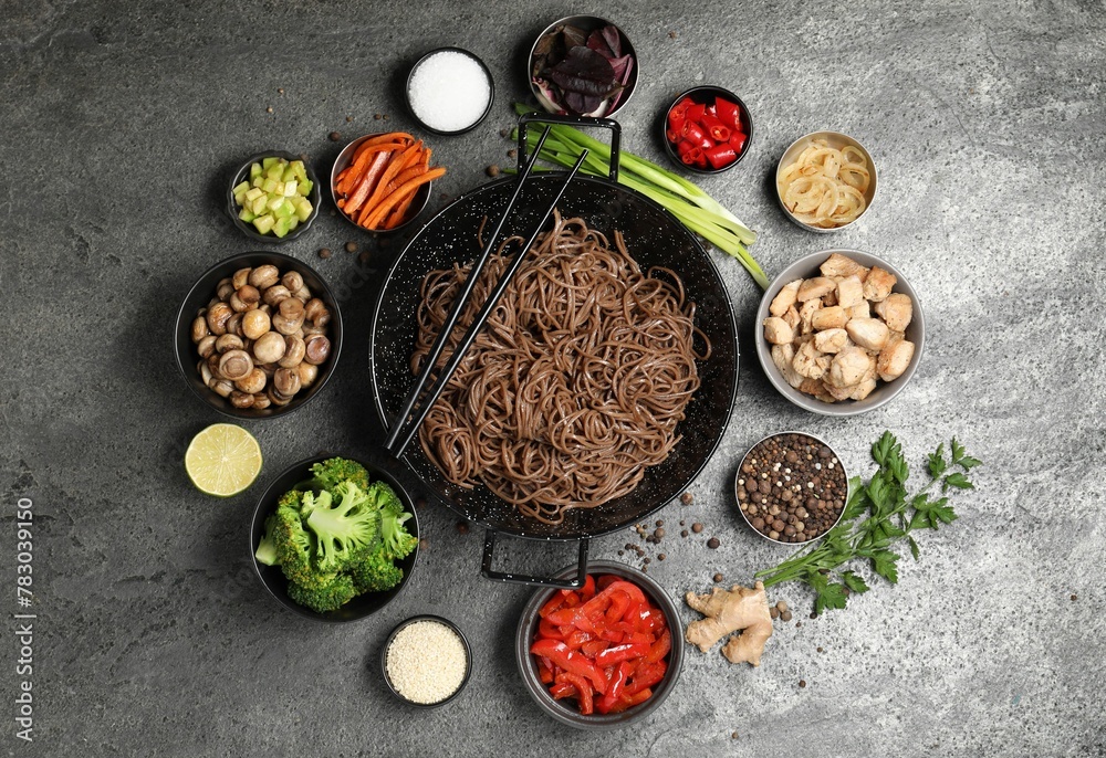 Wok with noodles, chicken and other products on grey table, flat lay