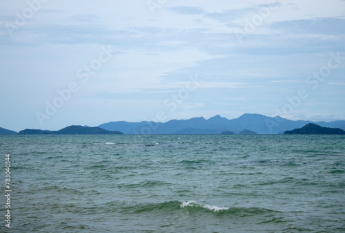 The ocean is calm and the sky is cloudy. The mountains in the background are visible