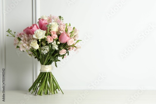 Beautiful bouquet of fresh flowers on table near white wall. Space for text © New Africa
