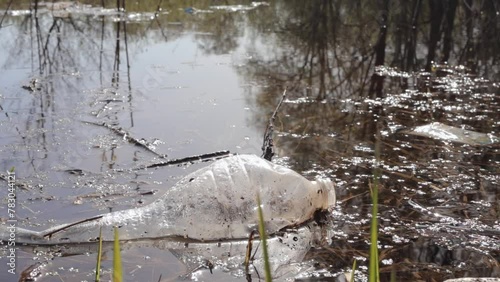 Water pollution environmental. Spilled garbage in river. Ecological problem. Empty plastic bottle floating on water photo