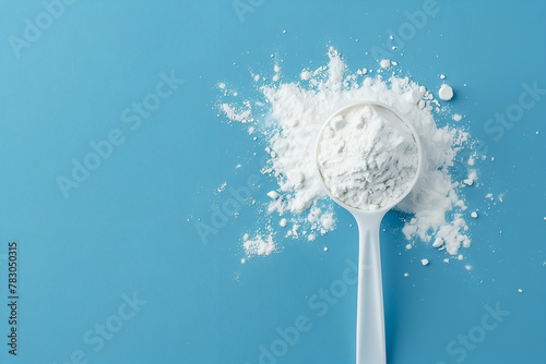 White creatine powder in a measuring spoon blue background, workout supplement for muscles and strength