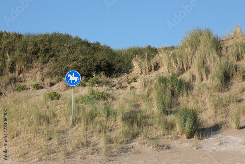 A sign indicating a horse riding trail in the dunes
