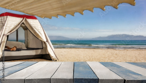 Wooden table in the blurred camping tent on the beach on a beautiful sunny day.Summer vacation, outdoor lifestyle. Cool and relaxing concept. For product display montage or key visual layout design. s photo
