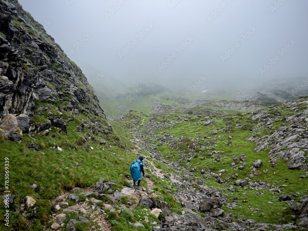 Man hike alone though the Bavarian mountains and he use a trash bag as his rain water protection Man hike alone though the Bavarian mountains and he use a trash bag as his rain water protection