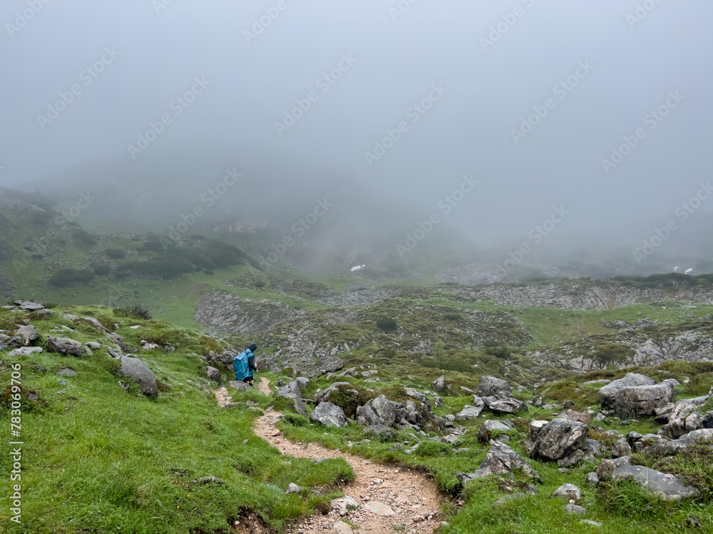 Man hike alone though the Bavarian mountains and he use a trash bag as his rain water protection Man hike alone though the Bavarian mountains and he use a trash bag as his rain water protection