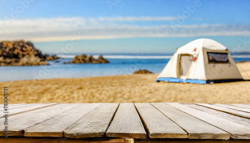 Fototapeta Naklejka Na Ścianę i Meble -  Wooden table in the blurred camping tent on the beach on a beautiful sunny day.Summer vacation, outdoor lifestyle. Cool and relaxing concept. For product display montage or key visual layout design. s