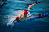 Powerful strokes. Freestyle swimming type. Young man, swimmer in motion training in swimming pool. Concept of professional sport, health, endurance, strength, active lifestyle