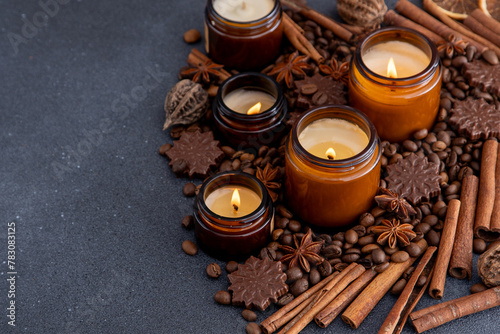 Soy scented candle in a jar. Coffee beans, anise, cinnamon spices. The candles are burning. Dark copy space background