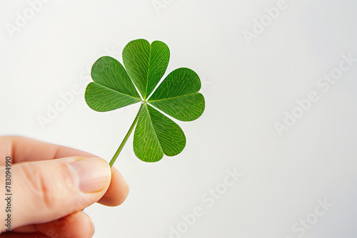 close up of a hand holding a st patricks four leaf clover, soft studio lighting, white color background, with empty copy space © Uwe