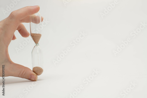 Unrecognizable female hand holding transparent hourglass photo