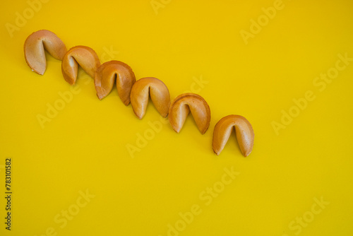 A fortune cookies are laid out in a line on yellow background. Minimalism and creative concept