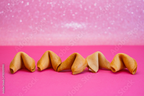 Fortune cookies are in a line on a pink and shiny background