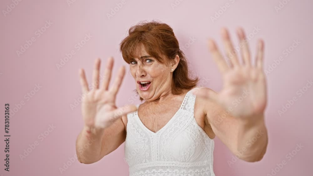 Terrified middle-aged woman wearing dress, shouting in panic, standing isolated over pink background, her hands showing stop signal, embodying fear concept Terrified middle-aged woman wearing dress, shouting in panic, standing isolated over pink background, her hands showing stop signal, embodying fear concept