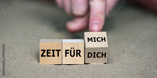 Hand turns cube and changes the German expression 'zeit für dich' (time for you) to 'zeit für mich' (time fo myself).