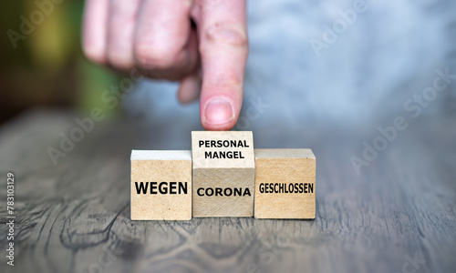 Hand turns cube and changes the German expression 'wegen Corona geschlossen' (closed due to corona) to 'wegen Personalmangel geschlossen' (closed due staff shortage)-